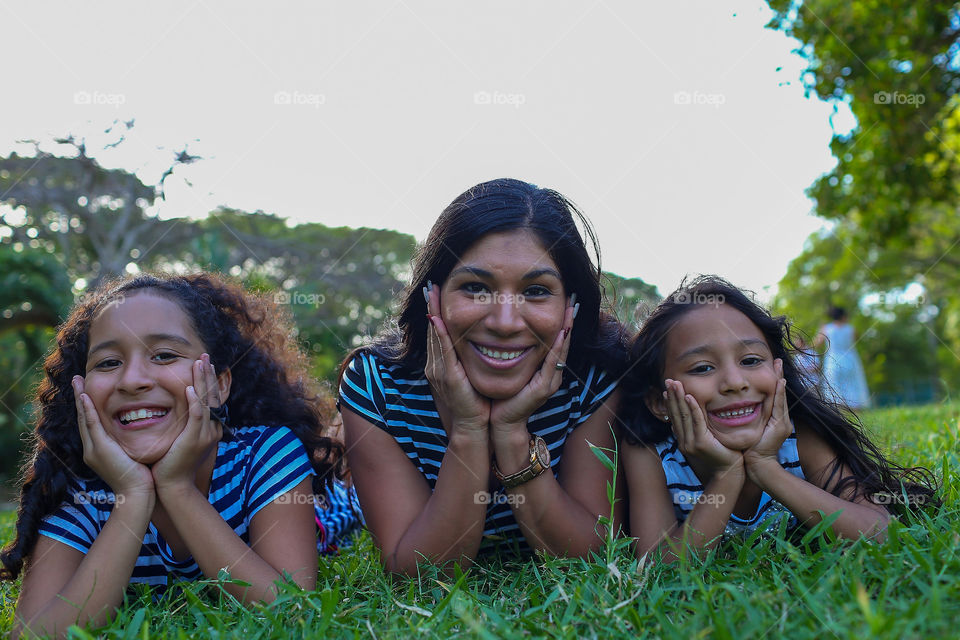 Mother and two daughters smiling straight to the camera 
