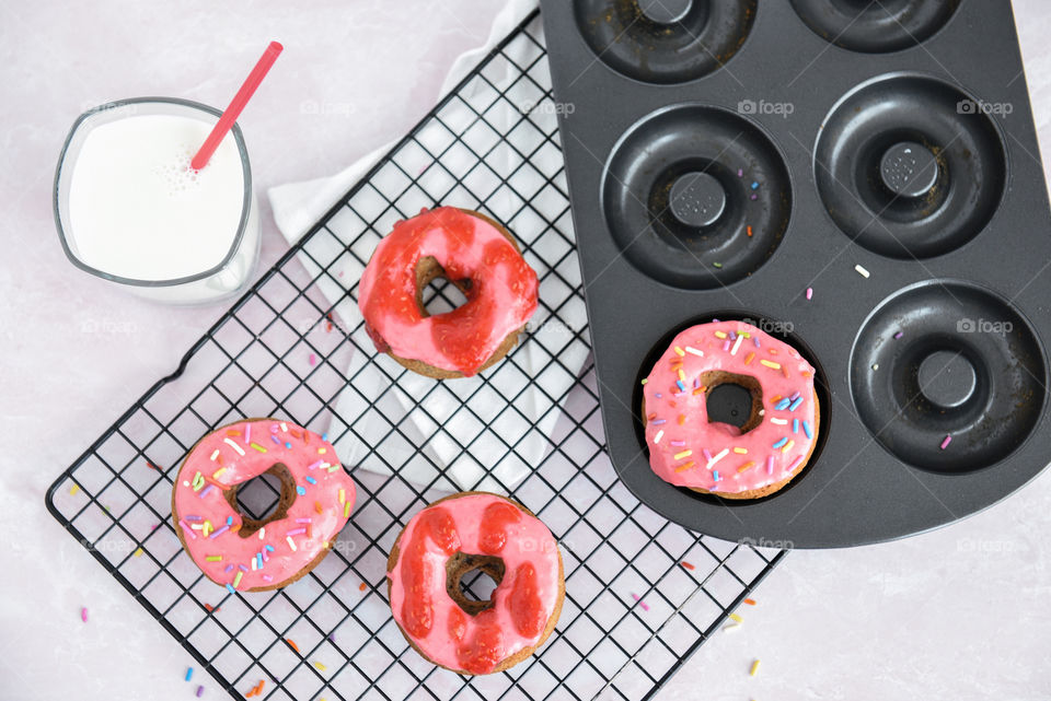 Flat lay of freshly baked homemade donuts and a glass of milk