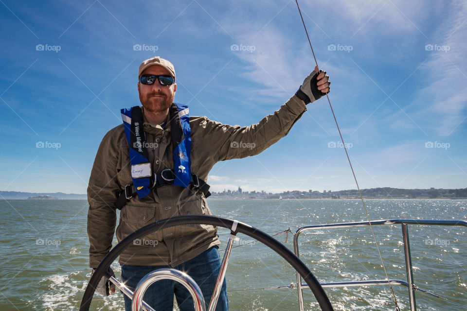 Man standing at helm of sailboat