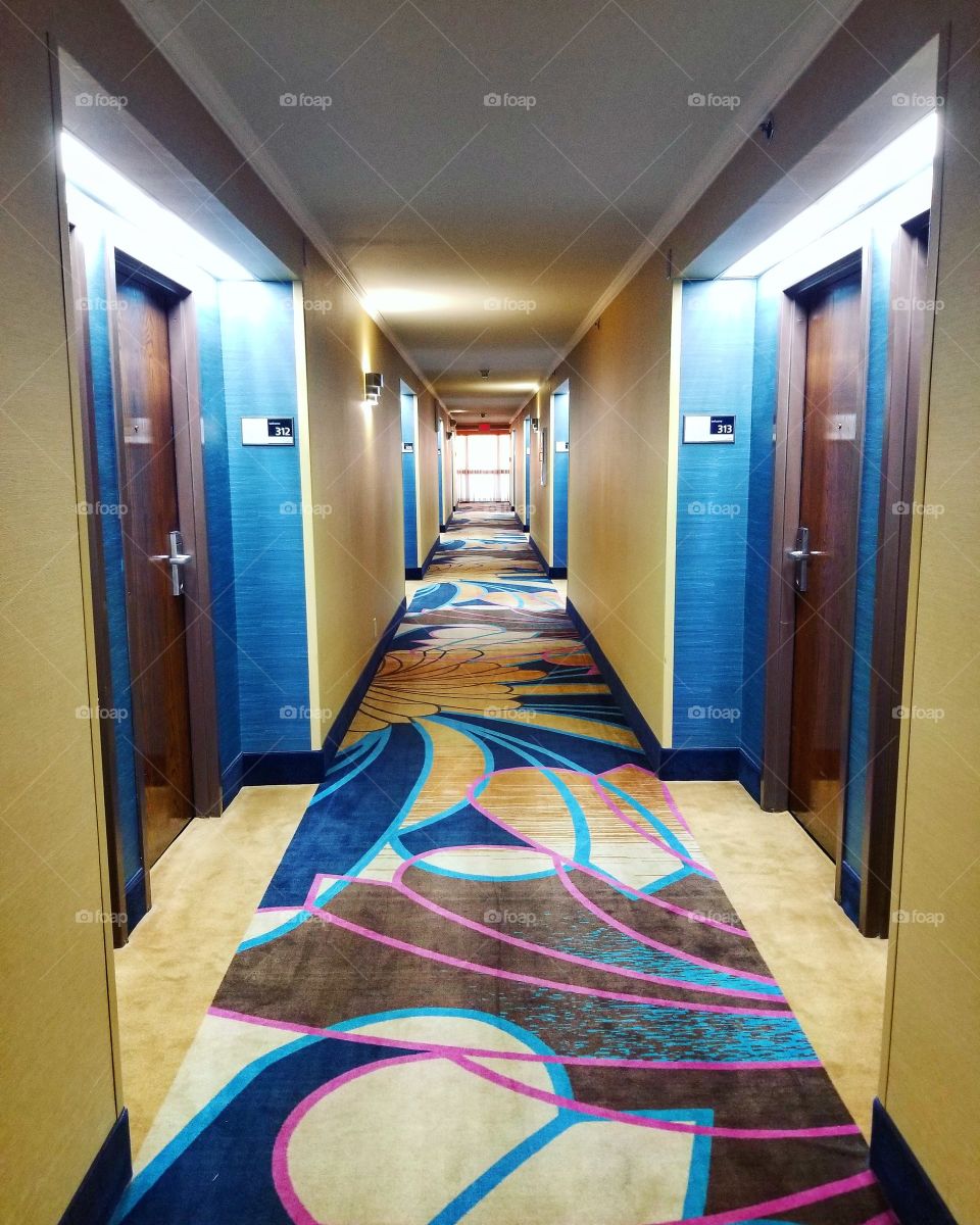 Empty Hotel Hallway with yellow and blue walls and yellow pink brown blue eclectic carpet