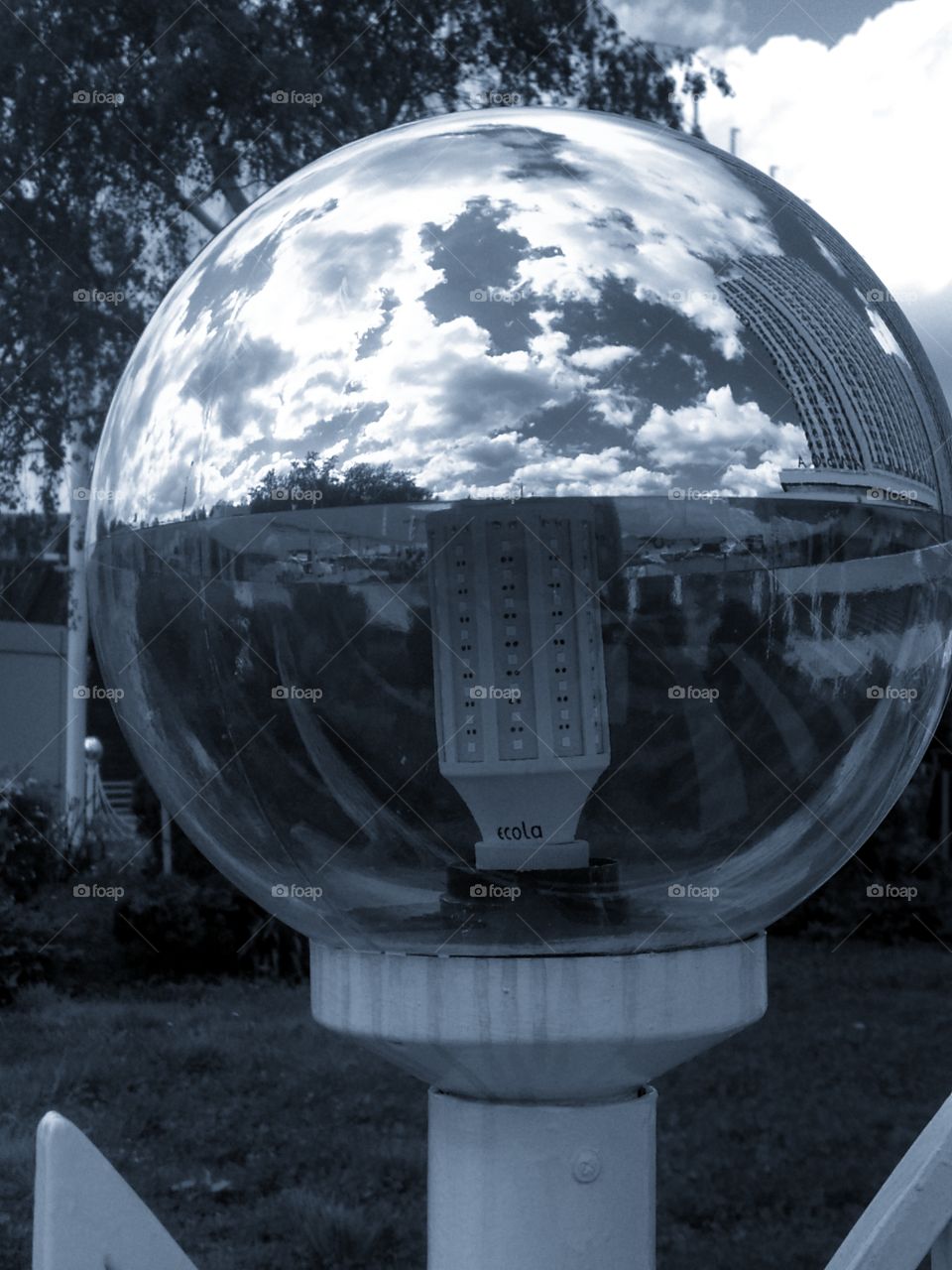Street lamp, the upper part of which reflects all objects in sight: sky, clouds, buildings