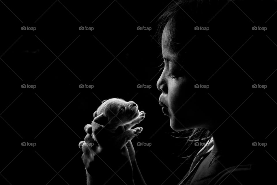 Cute girl holding puppy against black background