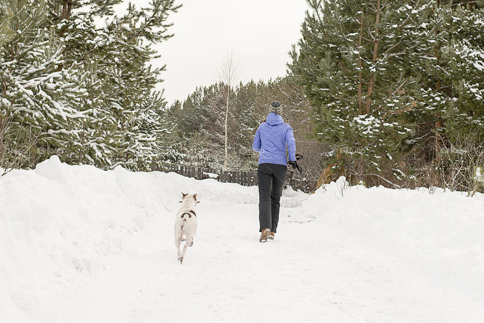 girl with dog running from snow road