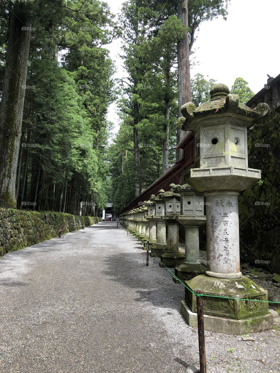 Row of concrete oil lamps along a secluded Japanese trail.