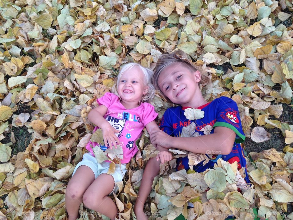 High angle view of boy and girl lying on autumn leafs