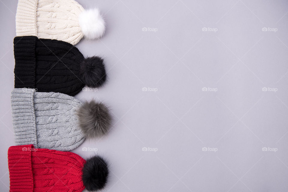 Flat lay of a row of different colored pom pom beanie hats