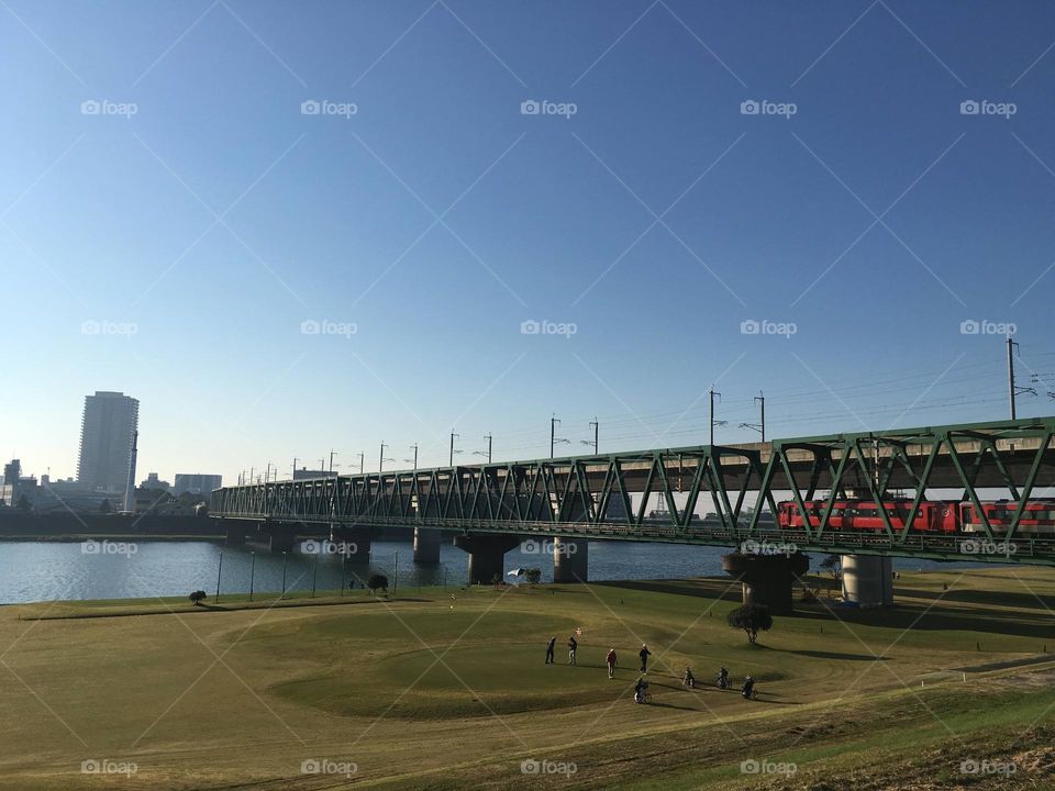 Tranquil Crossing: Tram Passing Over the River on a bridge in Kyushu,Kurume