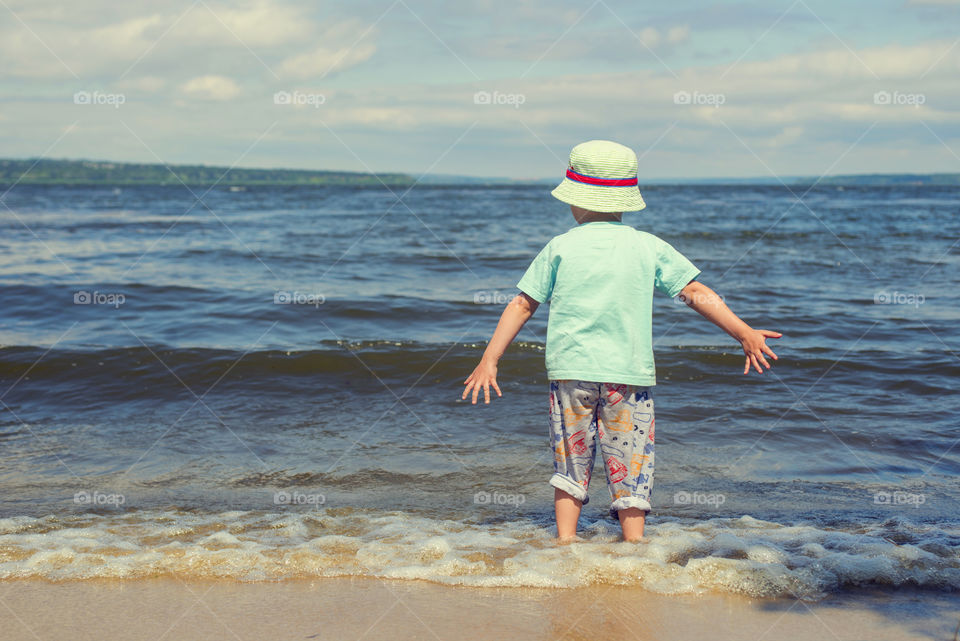 Little kid standing in the river during summer