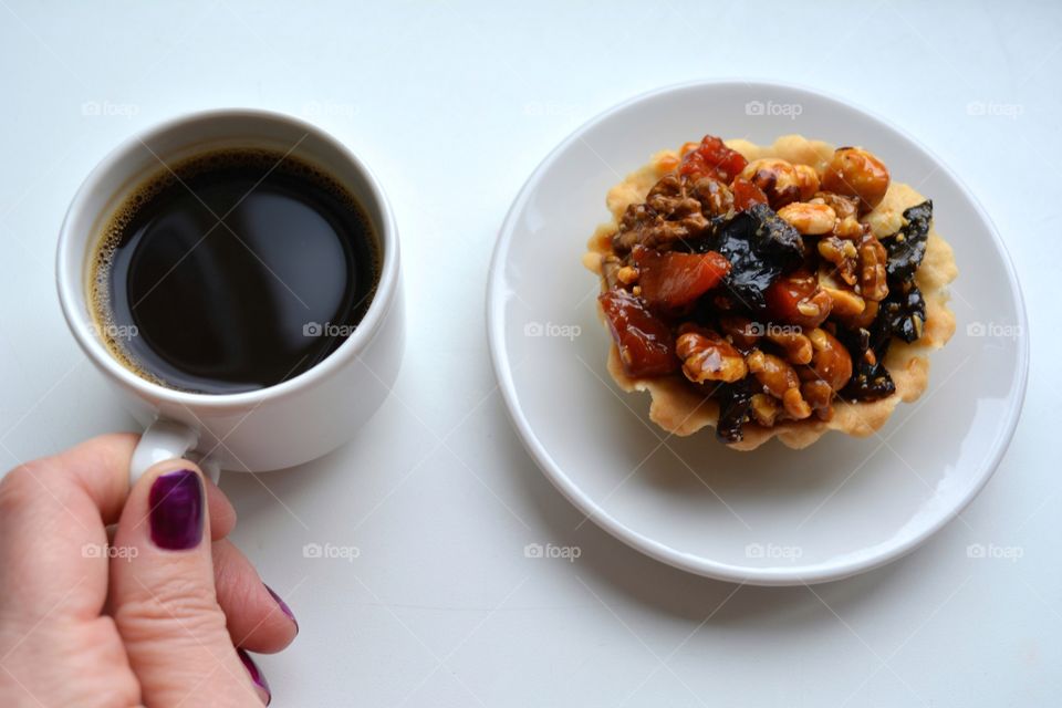 coffee mug in female hand and cake on a white background