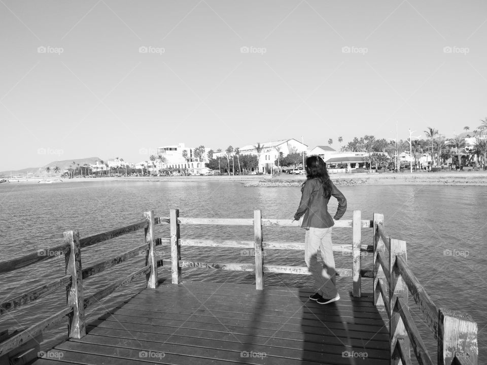 A woman on a wooden bridge looking at the coast