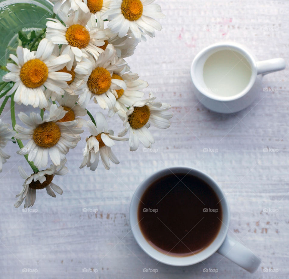 Flowers in vase with coffee on table