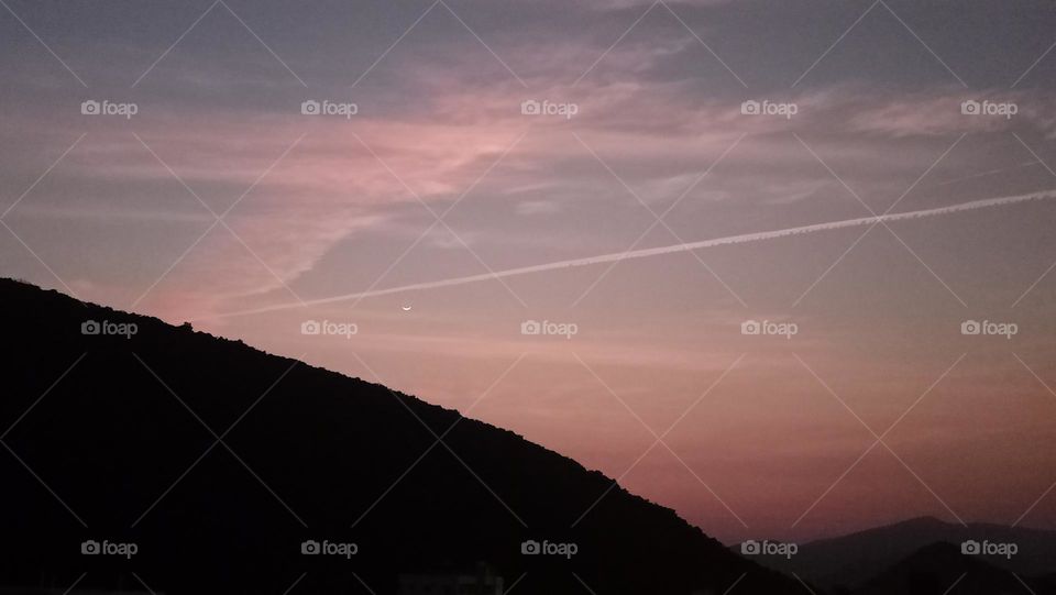 beautiful moon with jet contrails crossing at evening