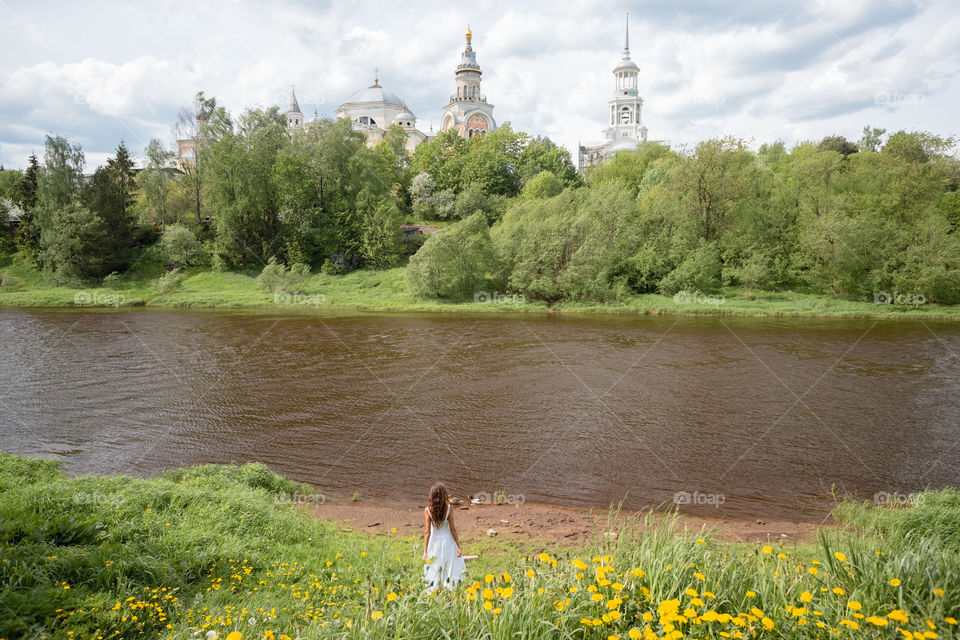 Russian village.  Girl standing near the river and looking at Russian churches
