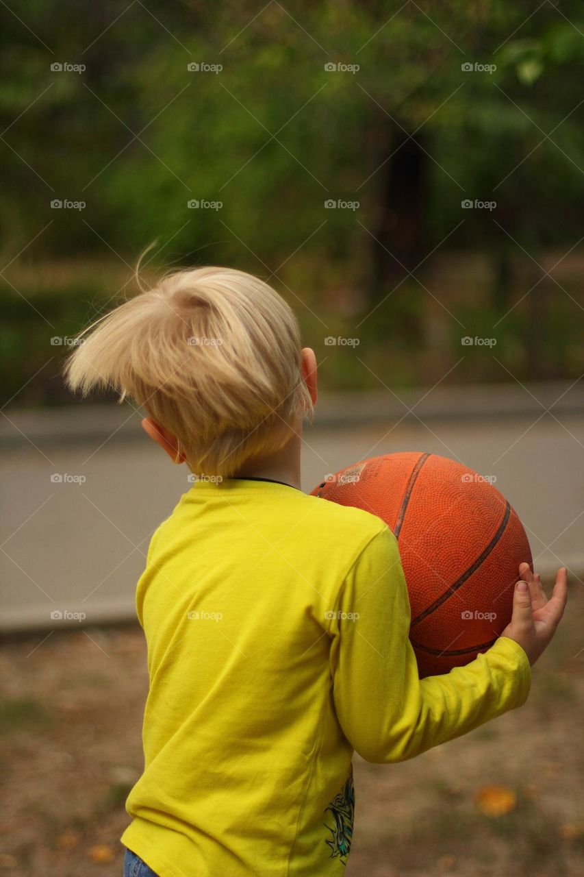 Little boy playing basketball in the yard