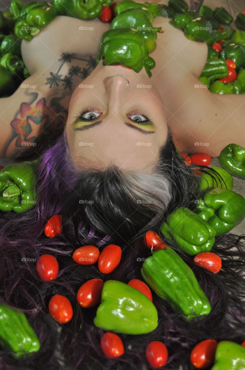 Topless woman lying upside down with capsicums and tomatoes