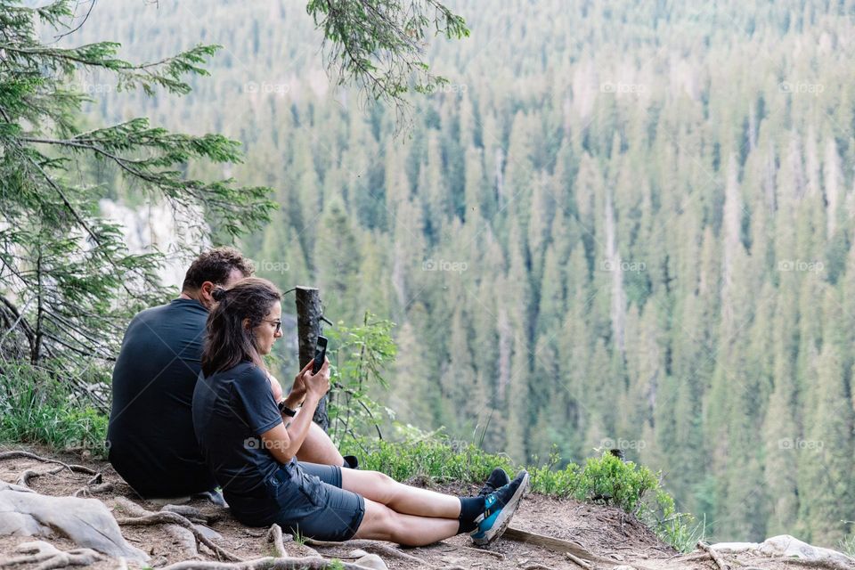 Young woman using her phone to take photos for social media, while doing a hike in the mountains.