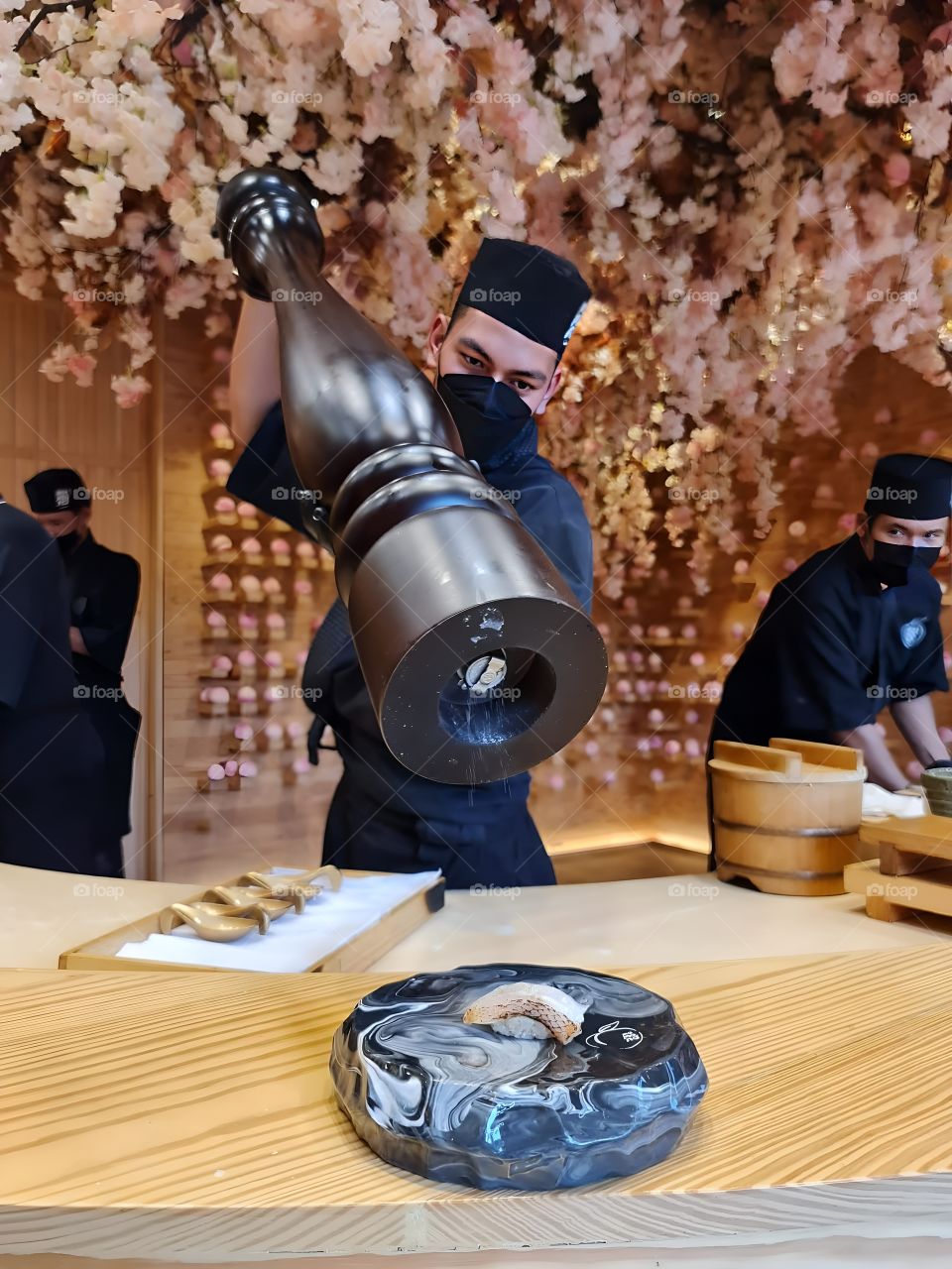 Chef sprinkles seasonings on sushi meticulously