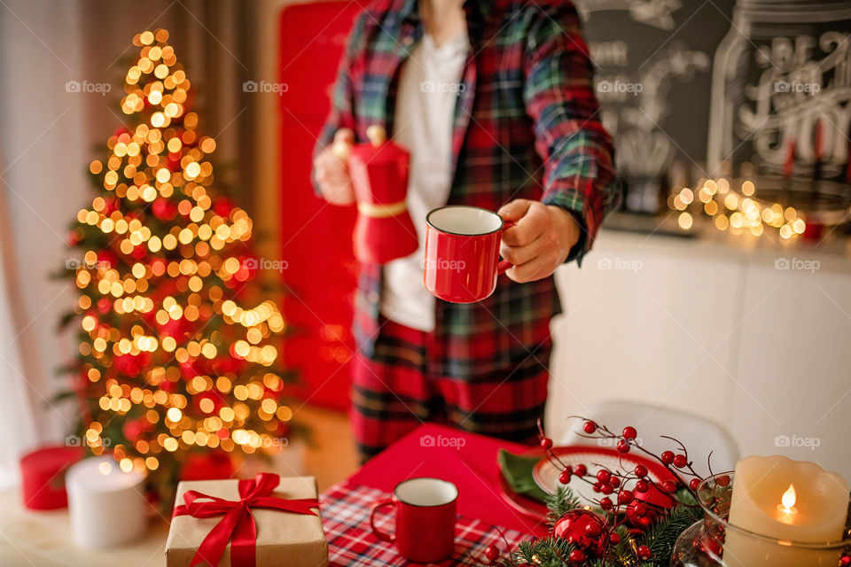 Festive winter cozy kitchen interior with garlands, decorations and gifts.  Christmas dinner at the decorated table.