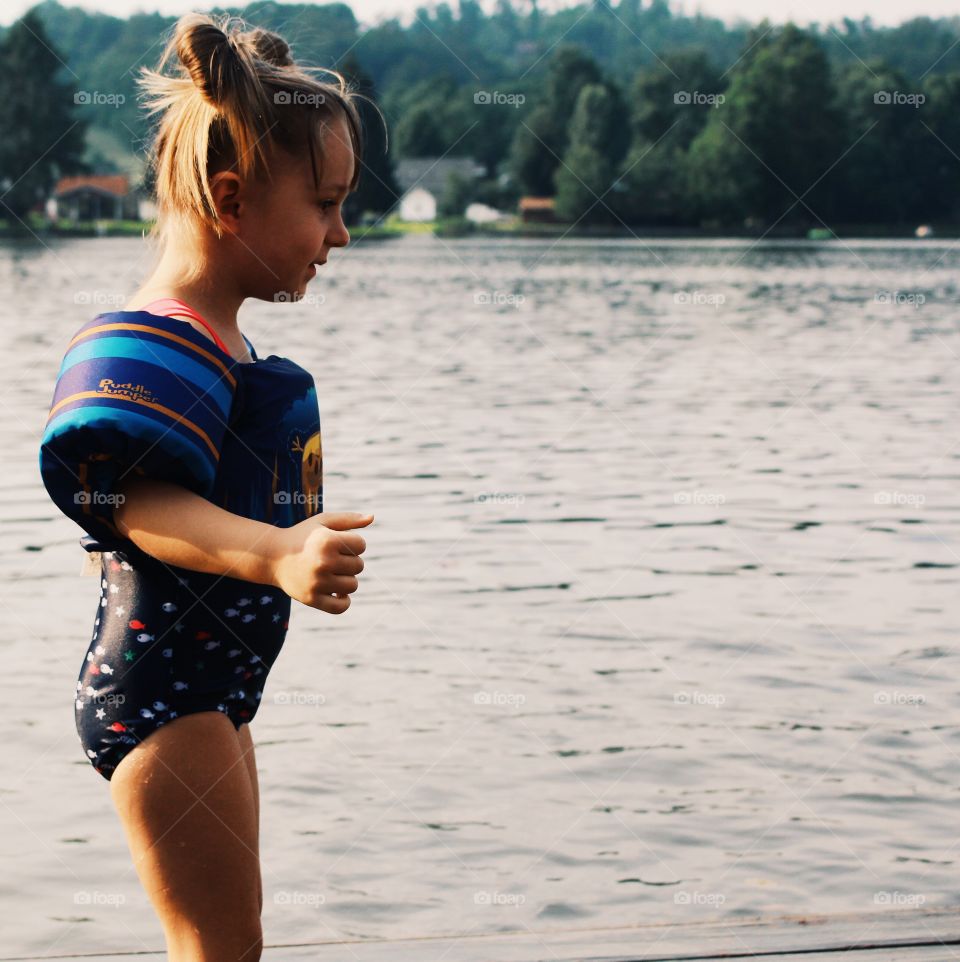 Girl in swimsuit standing near lake