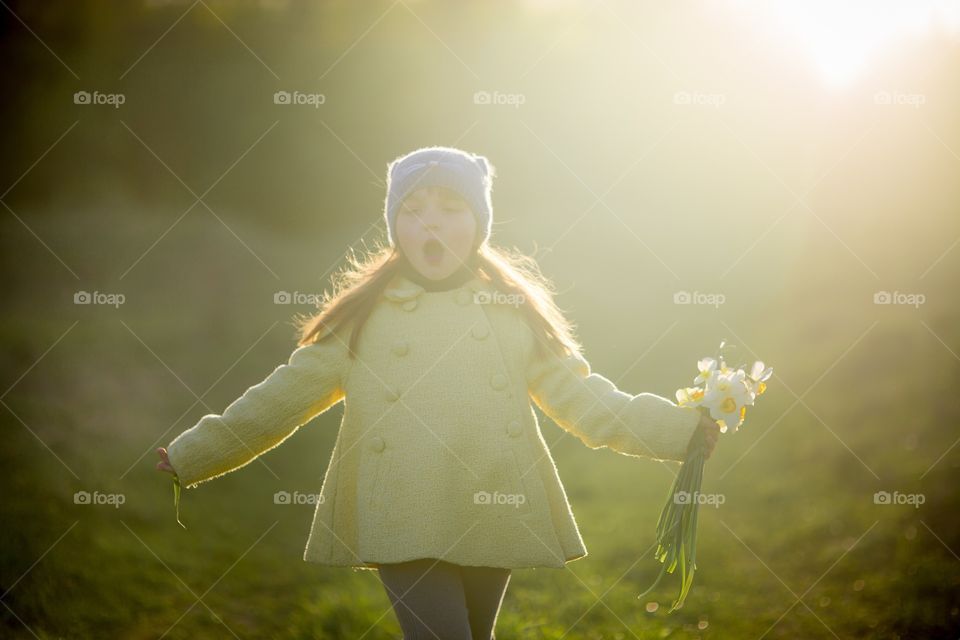 Little girl with narcissus bouquet in spring park