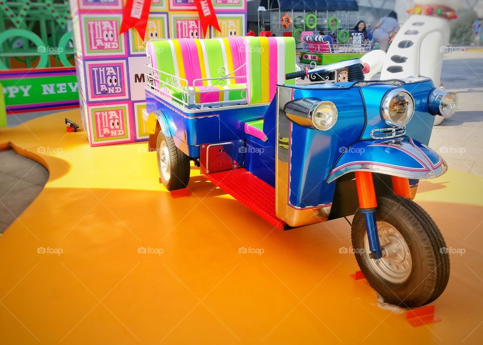 Static display of a colorful tuk-tuk outside a mall in Bangkok Thailand.