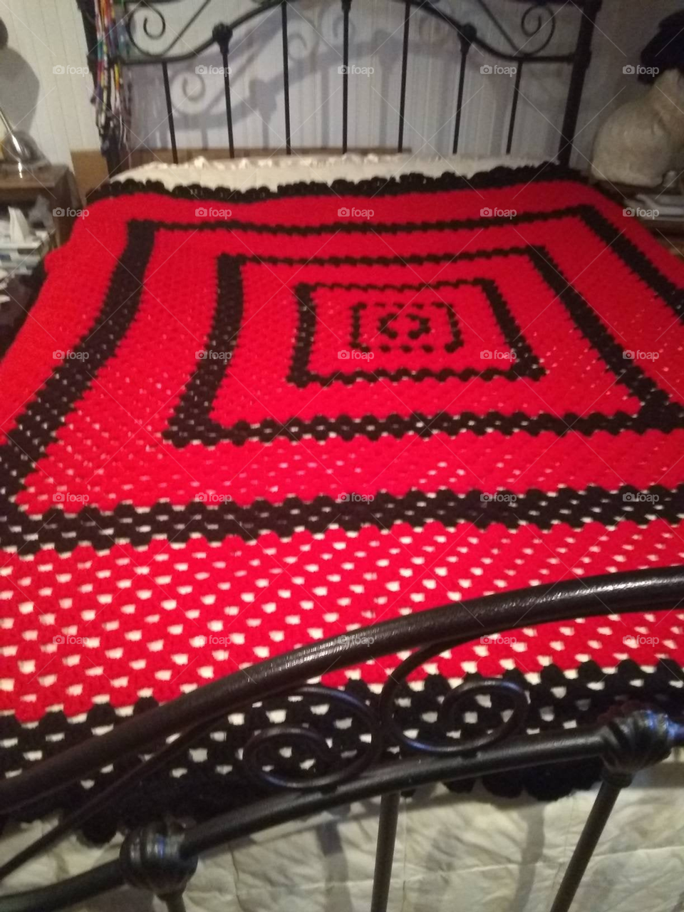 Red and Black Granny Square crocheted blanket on a queen size metallic frame bed.