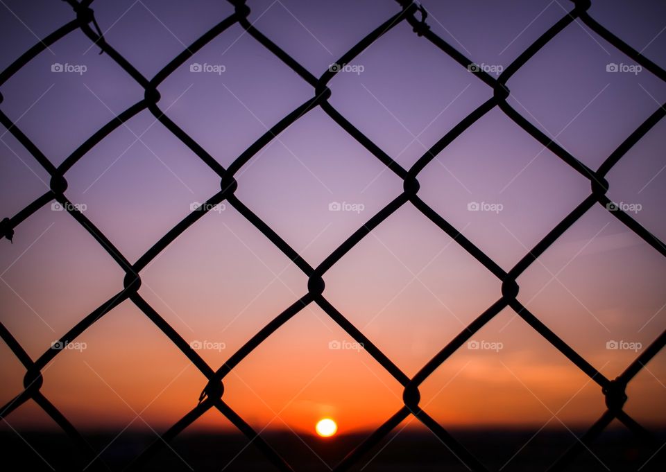 Silhouette of a metal fence at sunset. Beautiful sunset background.