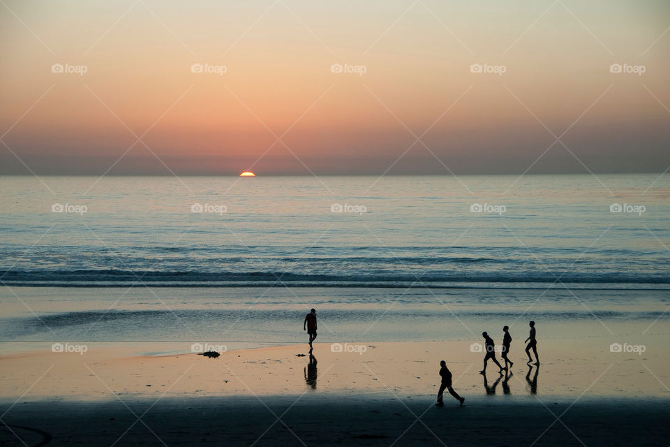 People playing on the beach at sunset