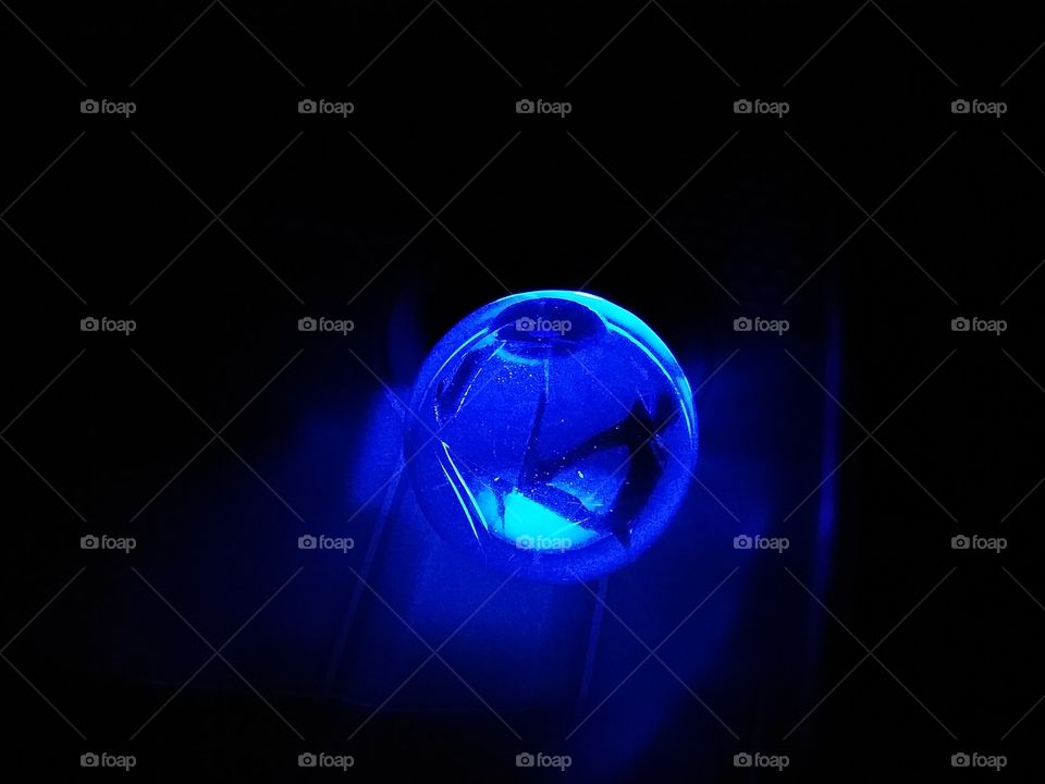 Glass orb illuminated from below by blue light.