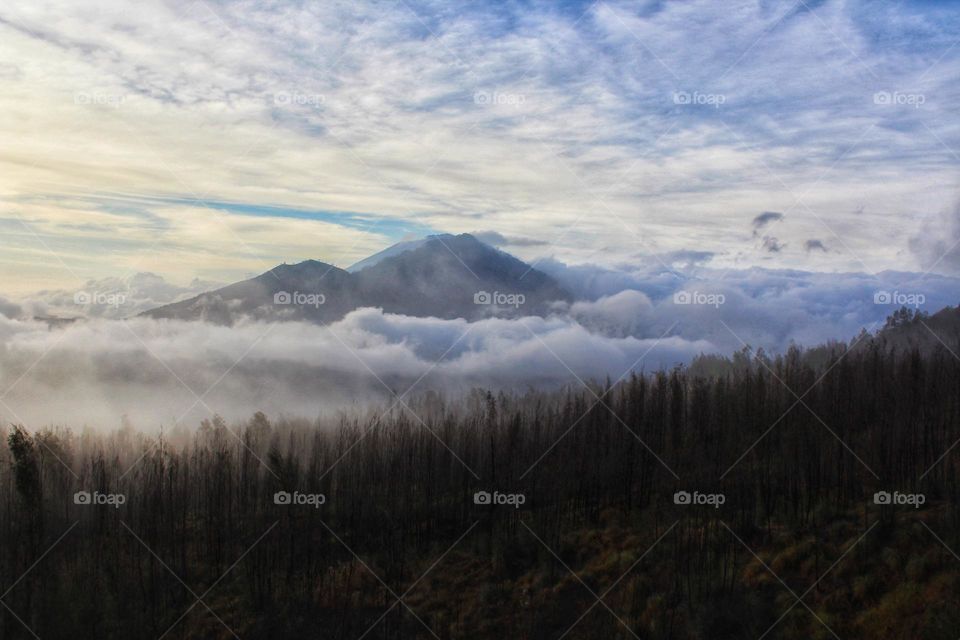 View from Mount Batur in Bali, Indonesia, after sunrise with clouds and early morning fog.