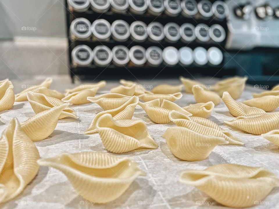 Making a pasta dinner at home, homemade pasta ready to cook, preparing homemade pasta, pasta shells with spice rack, view from the kitchen counter 