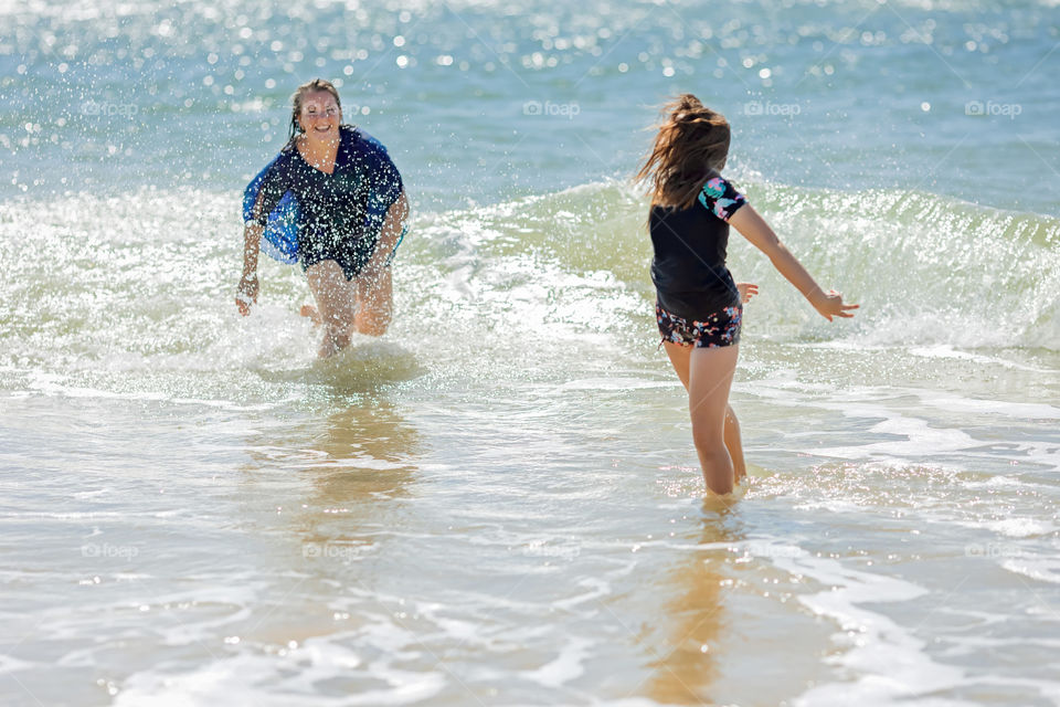 Woman with daughter having fun in the ocean waves 