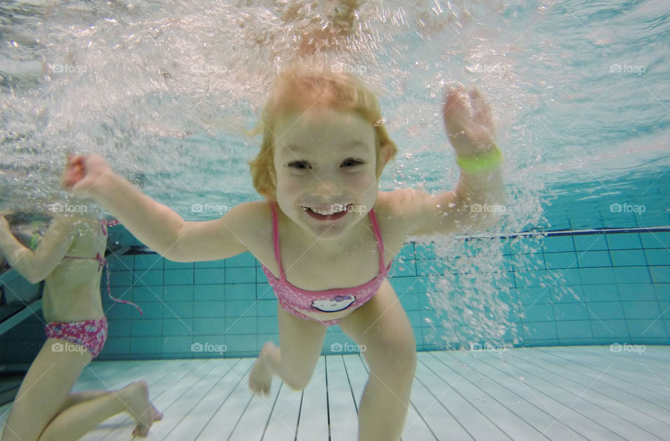 Two cute girls swimming in pool