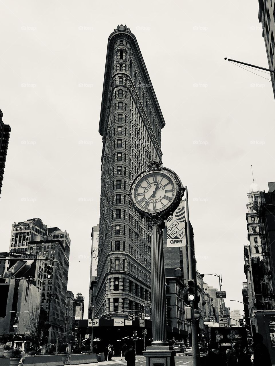 Low angle view of Flatiron building and street Tiffany clock on the 5th Avenue in New York, one of the most iconic architecturally unique building, iconic spot in black and white 