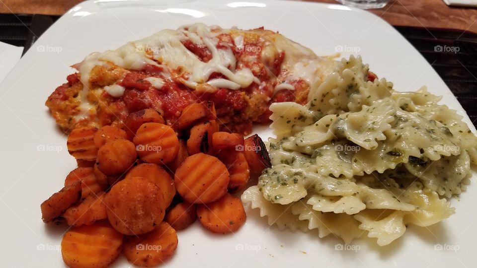 This is what's cookin' tonight, chicken parmigiana, bow tie pasta with pesto sauce and candied carrots.