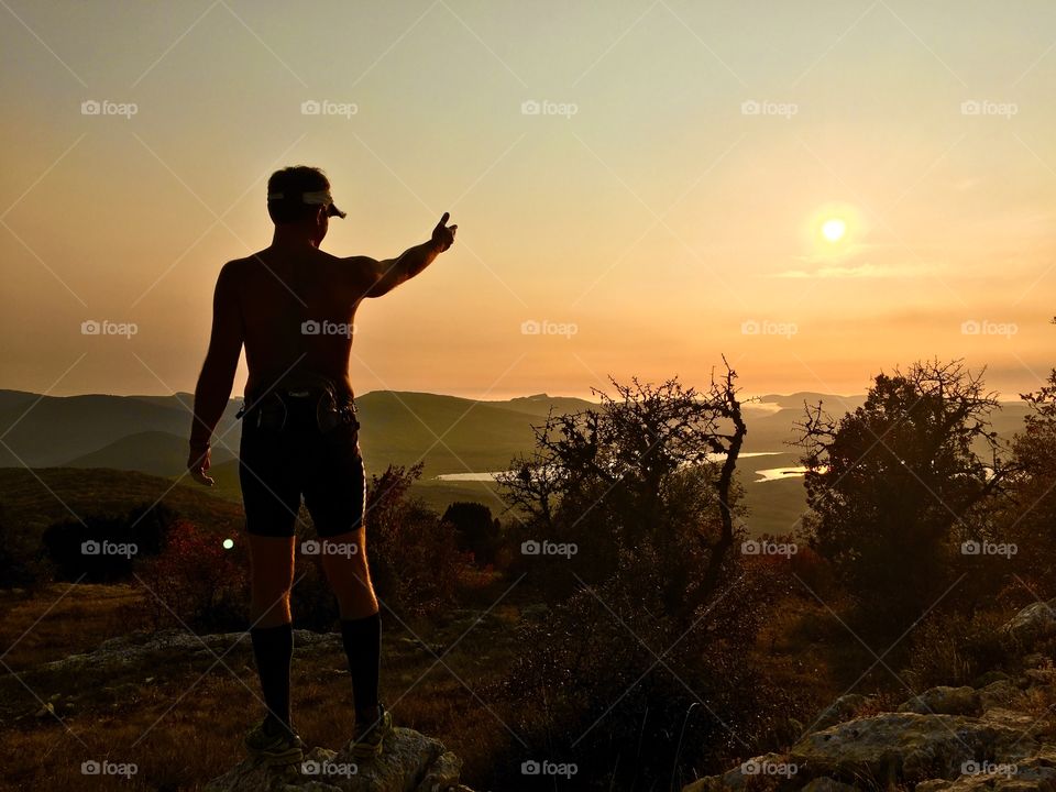 Silhouette of man enjoying the sunset on the top of the mountains. 