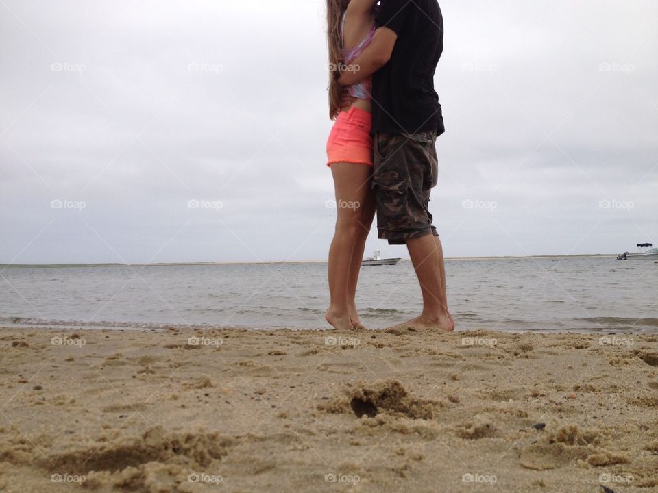 Stealing a kiss on a beach in Cape Cod, legs shown 