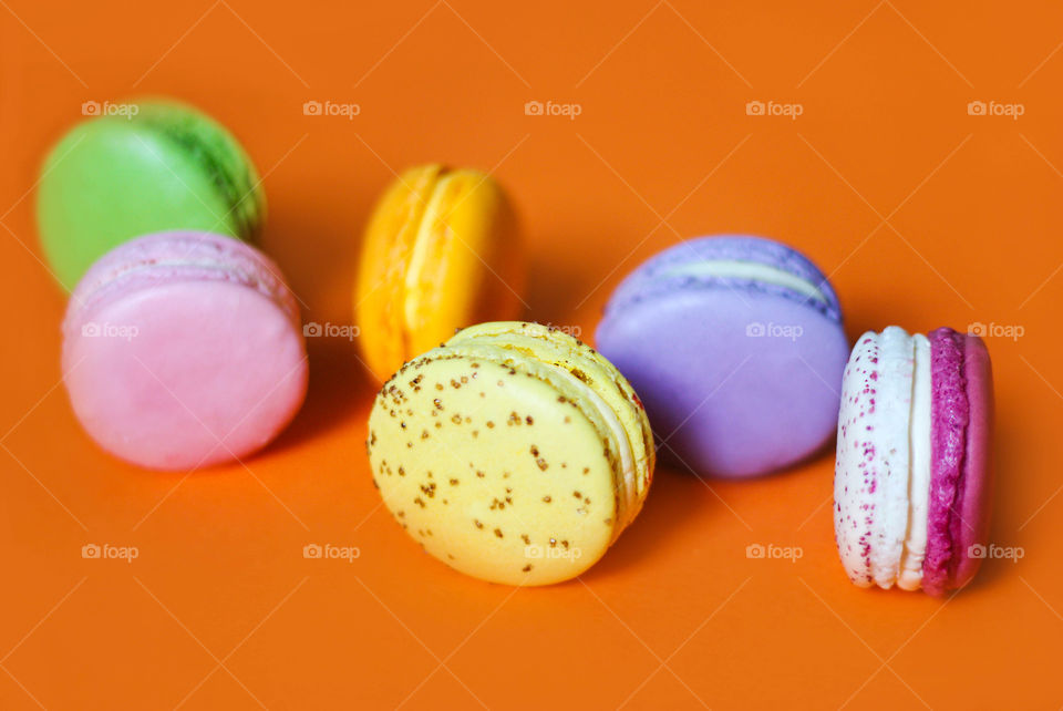 Colorful macaroon desserts, round shape, orange background