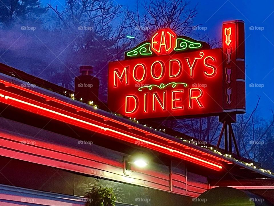 The neon lights on top of Moody’s Diner illuminate the darkening sky.