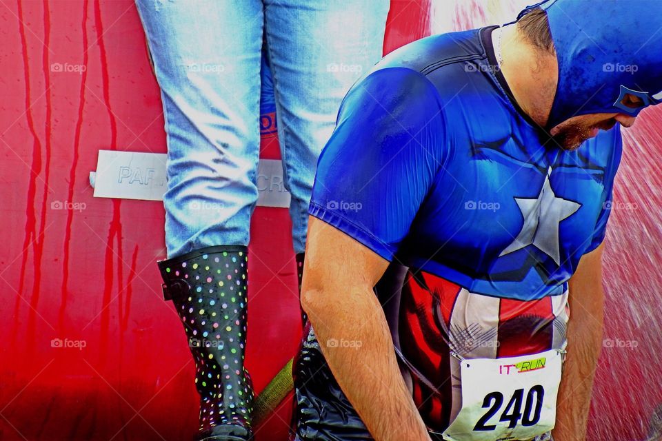 Jogger cooling off in a spray of water after a road race.