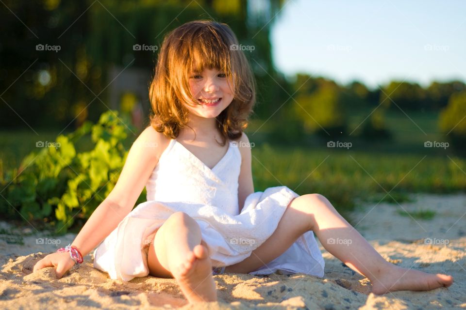 Happy girl sitting in sand