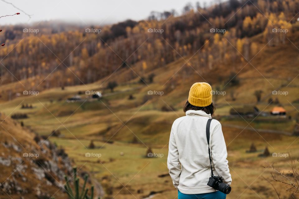 Woman standing in front of an autumn landscape, mesmerized by these beautiful colors, while on a hike.