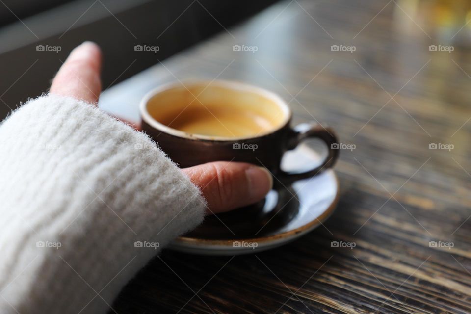 Hand touching the cup of espresso 