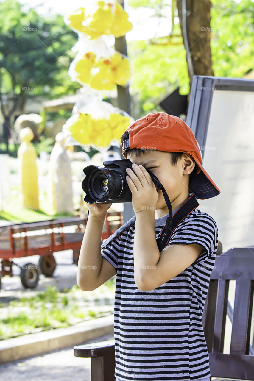 Hand boy holding the camera Taking pictures in park.