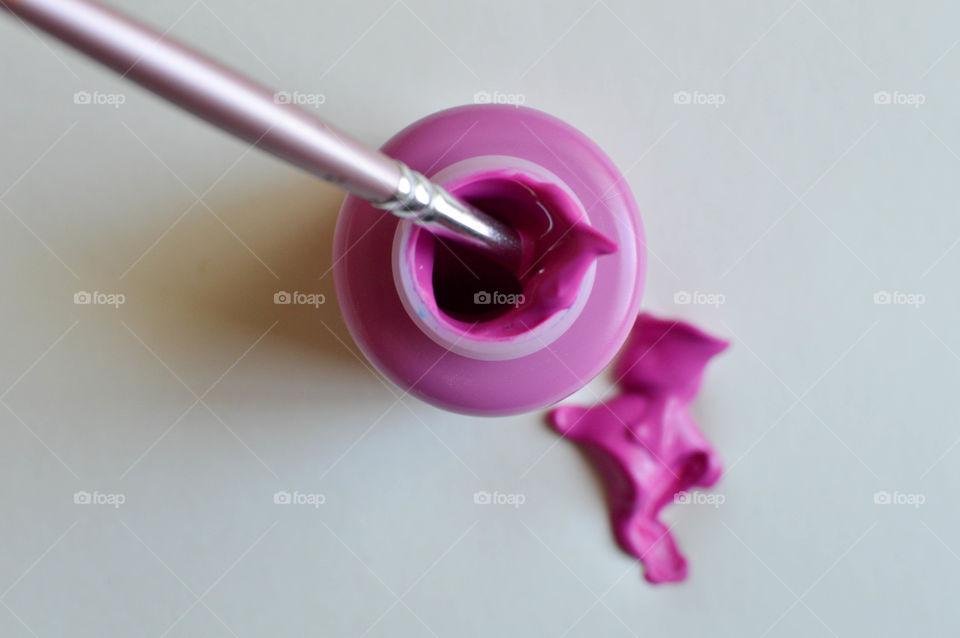 High angle view of pink paint bottle with paintbrush