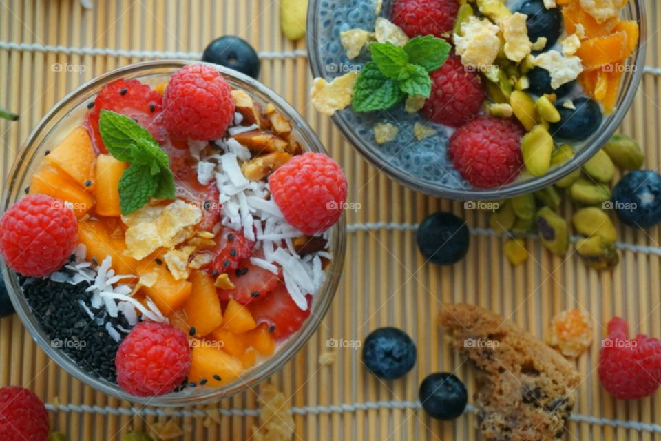 Healthy Fresh Fruit Smoothie Bowl - creamy raspberry smoothie topped with peach, seeds, dry coconuts,  nuts, blueberry and strawberry