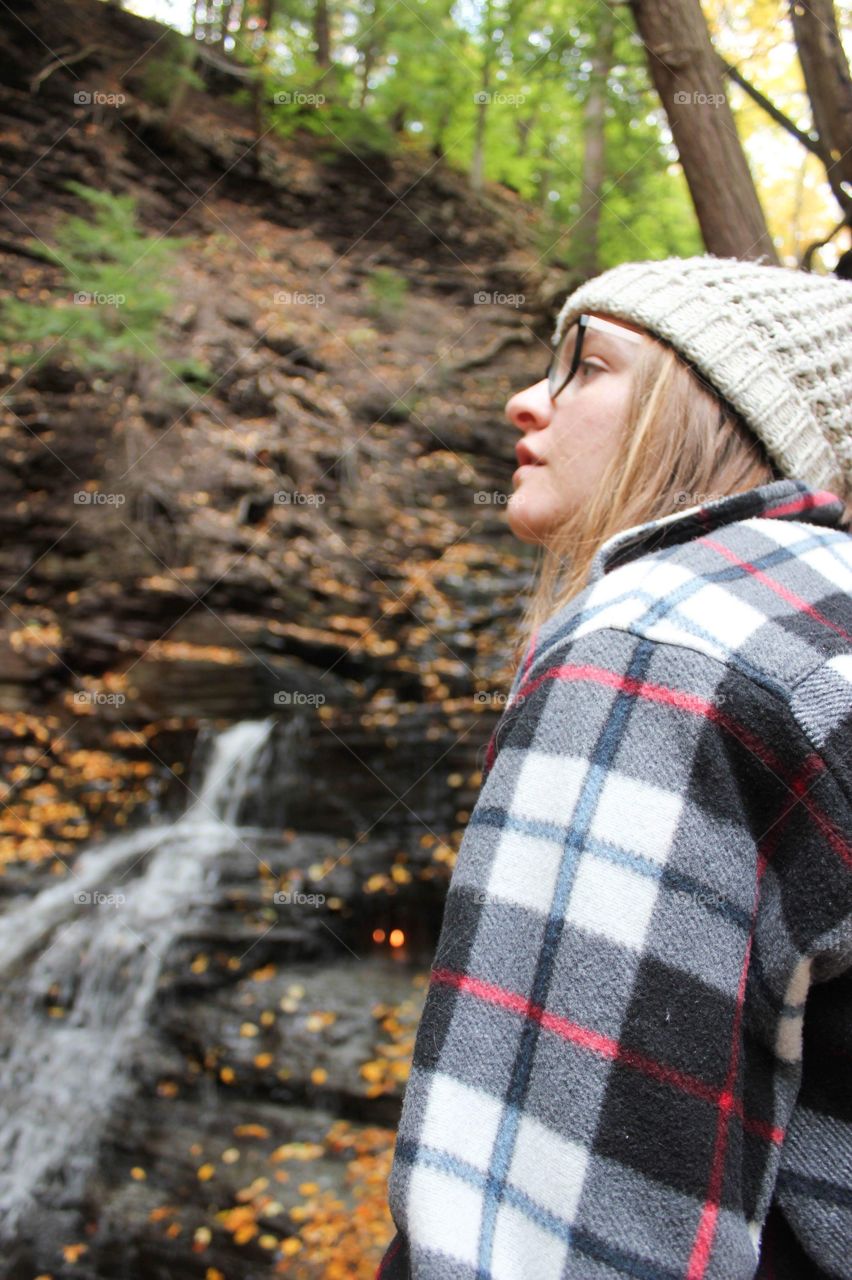 Young woman hiking near a waterfall in the autumn