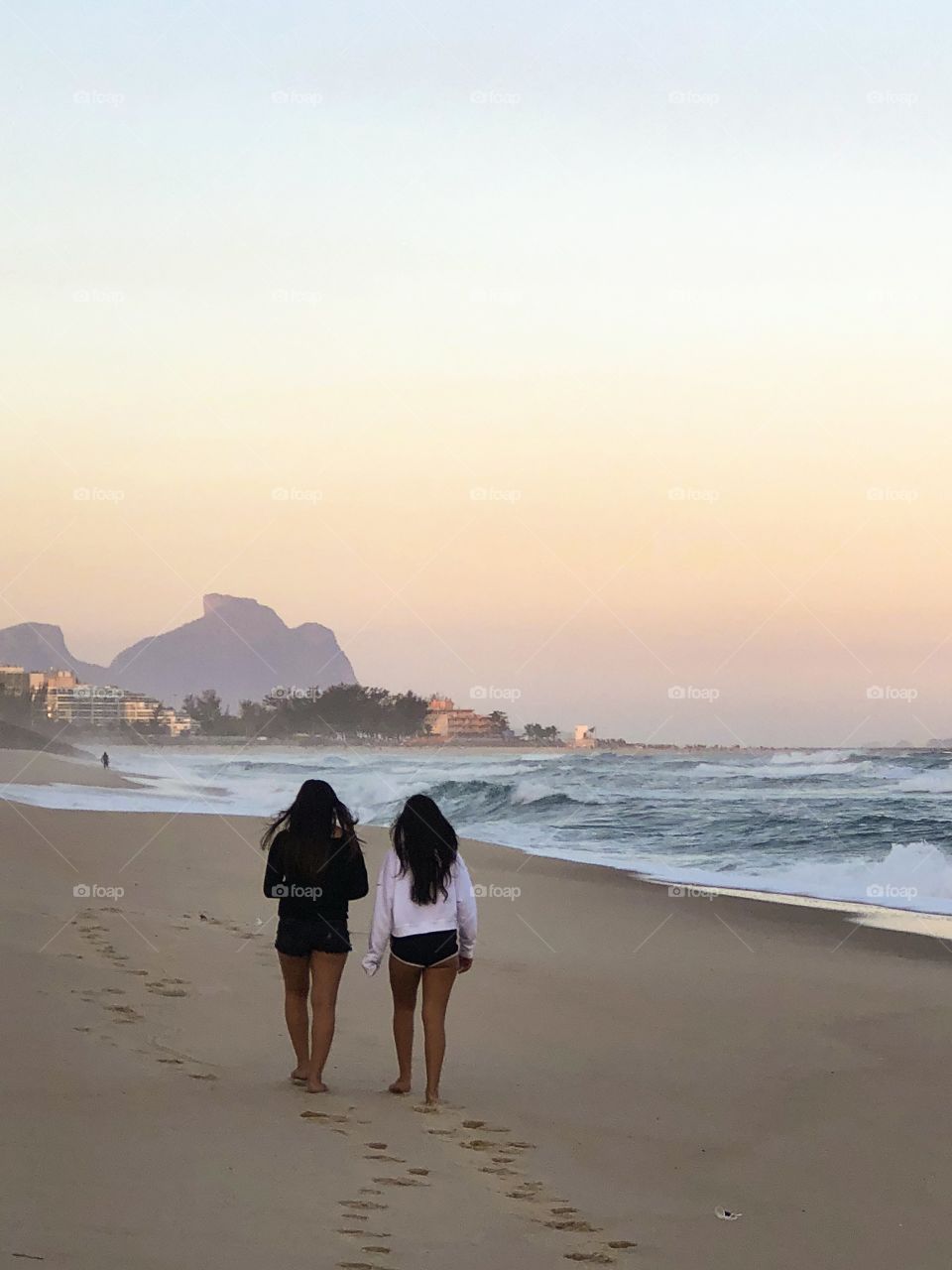 Two girls walking on the beach in a beautiful sunset