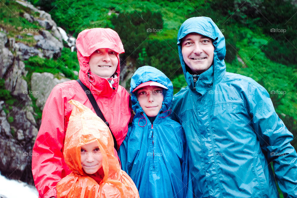 Family on mountain trail on a rainy day. Green slope in background