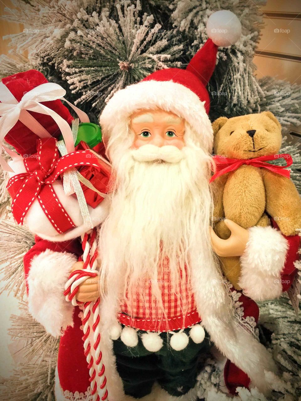 Santa Claus holding teddy bear and gifts